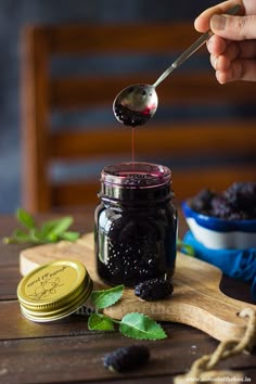 a spoon full of blackberries is being drizzled with syrup from a jar