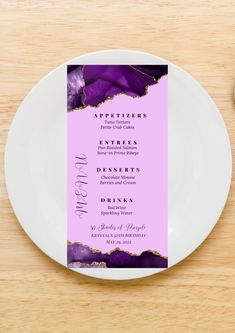 a white plate with a purple menu card on it next to a fork and spoon