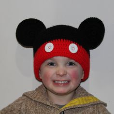 a young boy wearing a mickey mouse hat with buttons on it's ears and smiling at the camera