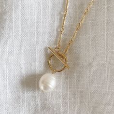 Dainty 14k gold filled necklace with a 8-9mm freshwater pearl and a toggle clasp Please note that each freshwater pearl is unique in shape and size so it will not look exactly like the one in the photos. Not all pearls are perfect and some may have dips/divots. Length: 18" If you would like a different length, please contact us for a custom order! Knot Necklace, Toggle Clasp, Freshwater Pearls, Gold Filled, Gold