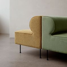 a green couch sitting on top of a gray floor next to a white wall in a living room