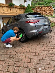 a young man is changing the tire on his sports car in front of a house