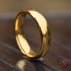 a gold wedding ring sitting on top of a wooden table