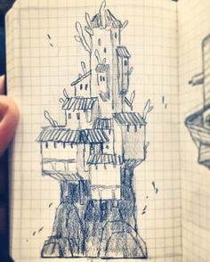 a hand holding up a drawing of a castle in the middle of a notebook with writing on it