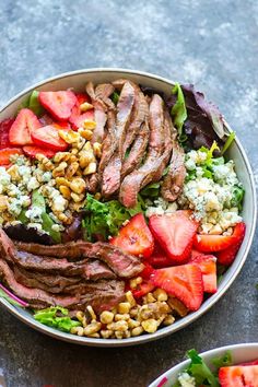 a bowl filled with meat and vegetables on top of a table next to another bowl