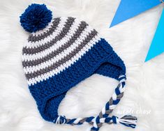 a crocheted blue and white striped hat with a pom - pom