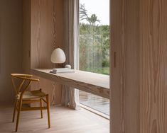 a chair and table in front of a window with wood paneling on the walls