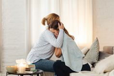 a woman is sitting on the couch with her head in her hands and she is covering her face