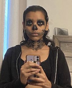 a woman in skeleton makeup holding a cell phone