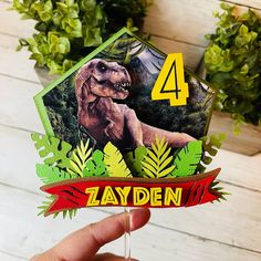 a hand holding up a birthday card with a dinosaur on the front and number 4 on the back