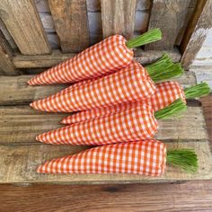 four carrots sitting on top of a wooden crate with green onions in the middle