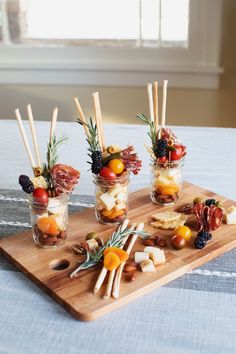 small jars filled with fruit and cheese on a wooden tray