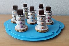 there are many small snowmen made out of cookies on a blue platter with chocolate