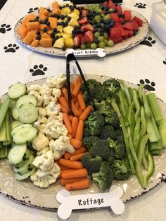 two platters filled with veggies on top of a table next to a dog bone