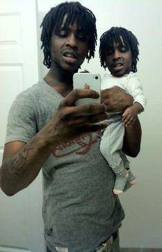 a man holding a baby and taking a selfie in front of a mirror with his cell phone