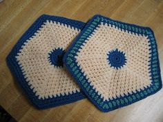 two crocheted blue and white coasters sitting on top of a wooden table