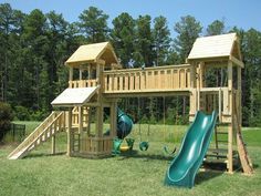 a wooden playset with a slide and climbing frame in the grass near some trees