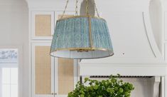 a lamp hanging from the ceiling above a table with a potted plant on it