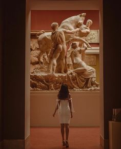 a woman standing in front of a large statue with statues on it's sides