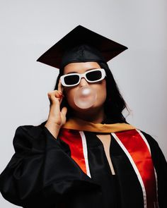 a woman wearing sunglasses and a graduation cap is making a funny face with her nose