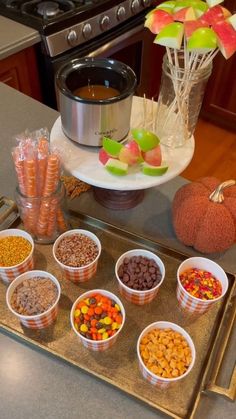 a tray filled with candy and candies next to a crock pot on a stove