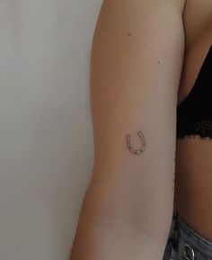 a woman's arm with a small horseshoe tattoo on the left side of her right arm