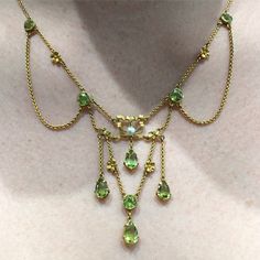 This Edwardian peridot and pearl necklace in its fitted box epitomises the pretty and light look of the early 20th century.  The heavy, solid fashions of the Victorian era were banished, along with the 1800s.  Peridots and other pale-hued stones came into vogue. Festoons and swags - as seen here - harking back to Georgian times were reinvented.  I love the rich, buttery gold framing the brilliance of the green gemstones - and the sweet little gold flowers scattered among them.  FREE WORLDWIDE EX Crazy Shirts, Bijoux Art Nouveau, Natural Pearl Necklace, Edwardian Jewelry, Fairy Jewelry, Natural Pearl, Victorian Jewelry, Fantasy Jewelry, Multi Strand Necklace