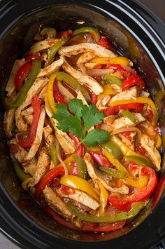 chicken and peppers in a slow cooker with cilantro garnishes