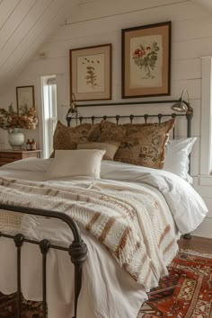 a bed with white sheets and pillows in a bedroom next to two framed pictures on the wall