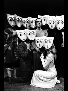 a group of people standing next to each other with masks on their faces in front of them