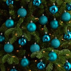 blue ornaments are hanging from the branches of a christmas tree