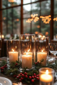 candles are lit on a table with greenery