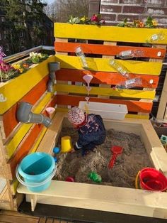 an outdoor play area made out of pallets and wooden boards with sand in it