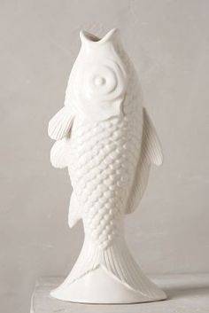 a white fish shaped vase sitting on top of a table