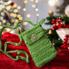 a green crocheted purse sitting on top of a red blanket next to a christmas tree