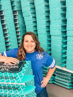 a woman standing in front of stacks of blue boxes with the word shop on it