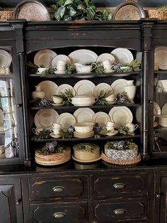 a black china cabinet filled with dishes and plates