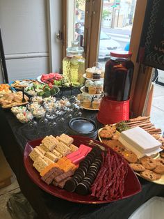 an assortment of desserts and snacks are on a table in front of a window