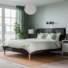 a bedroom with a bed, dresser and large window overlooking the city outside in front of it