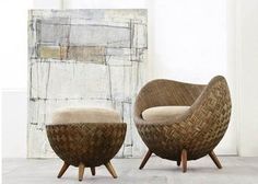 two wicker chairs sitting next to each other in front of a painting on the wall