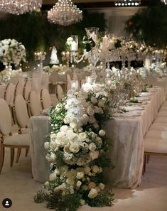 the table is set up with white flowers and crystal vases for centerpieces