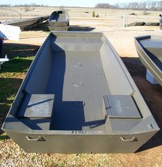 two boats are parked on the grass next to each other, one is empty and the other has no people in it