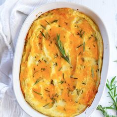 a casserole with cheese and herbs in a white dish on a white table