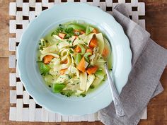 a white plate topped with pasta and veggies on top of a wooden table