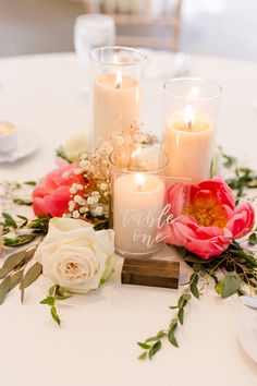 candles and flowers on a table with greenery