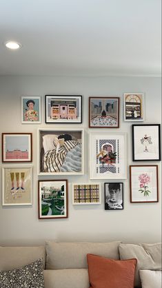 a living room filled with lots of framed pictures on the wall next to a couch