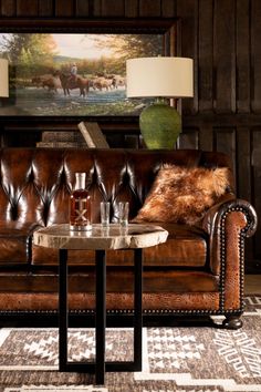 a brown leather couch sitting next to a table with a lamp on top of it