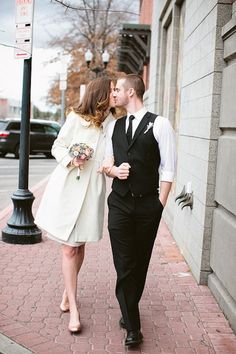 a man and woman are walking down the street kissing each other while wearing formal attire