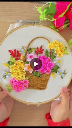 someone is working on an embroidery project with flowers in a basket and the video shows how to make it