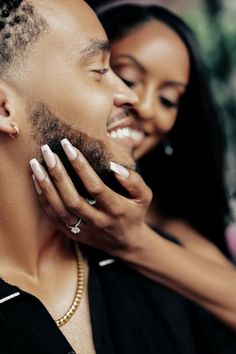 a man and woman smile as they hold each other's neck in front of the camera